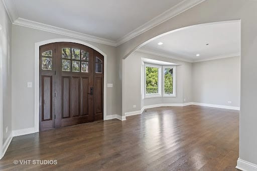 Bright open entryway with dark wood door and hardwood floors
