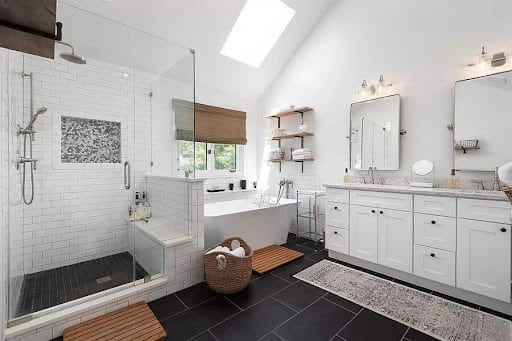 Bright white bathroom with freestanding tub, walk-in shower, and dark tile floors