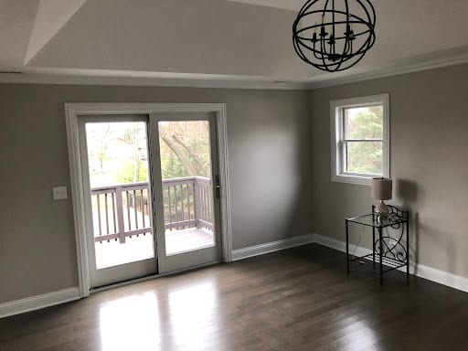 Empty room with gray walls, dark hardwood floors, and sliding glass door to deck