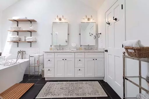 White double vanity bathroom with dark tile floors and freestanding tub