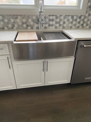 Stainless steel farmhouse sink with cutting board and hex tile backsplash