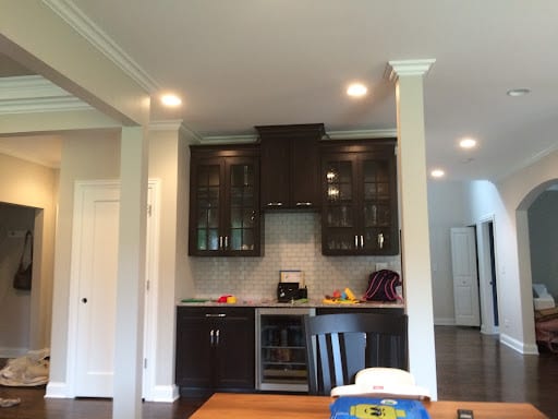Dark wood cabinetry with glass doors and wine cooler in open kitchen