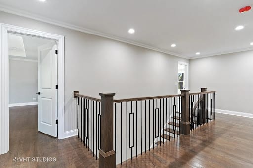 Open upstairs hallway with dark wood and metal stair railing system