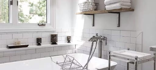 White subway tile bathroom with clawfoot tub and wooden shelf