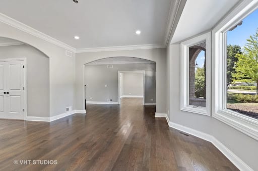 Open living area with dark hardwood floors, arched doorways, and gray walls
