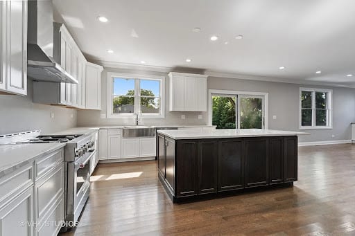 Open kitchen with white cabinets, dark island, and hardwood floors