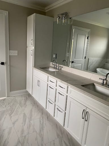 White double vanity with gray countertop and marble tile floor in remodeled bathroom