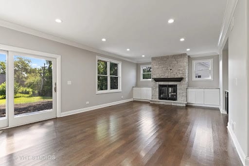 Empty living room with dark hardwood floors and stone fireplace