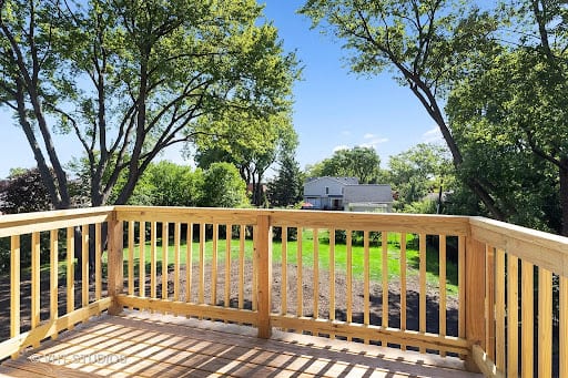 Newly built wooden deck with railings overlooking a green backyard