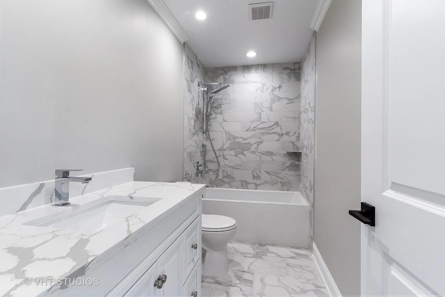 White marble tile bathroom with soaking tub, vanity, and chrome fixtures