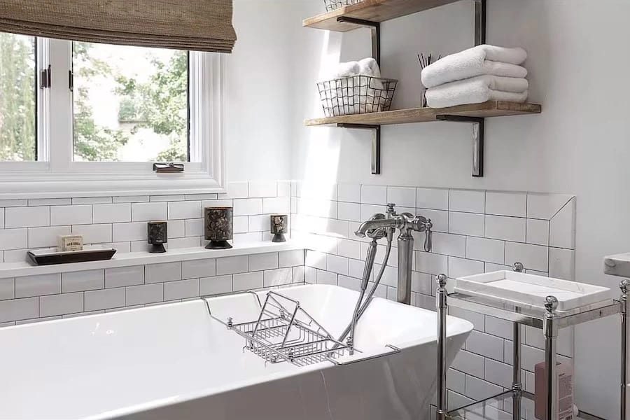 Freestanding white soaking tub with chrome fixtures and white subway tile walls