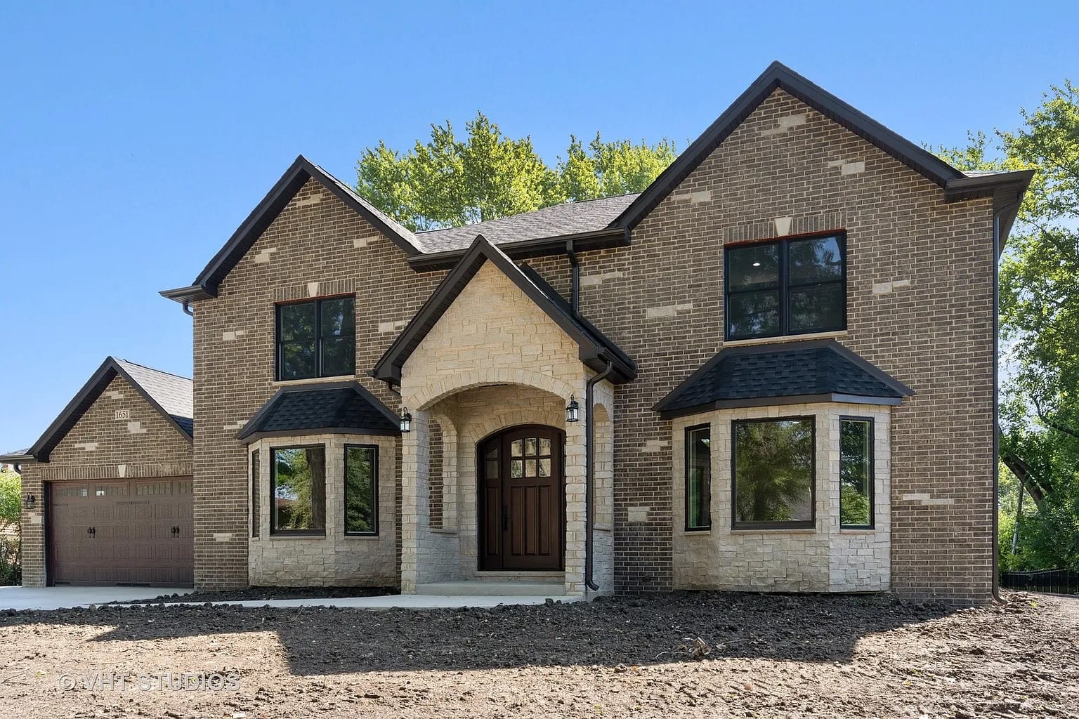 Newly built two-story brick and stone home with arched entryway and attached garage