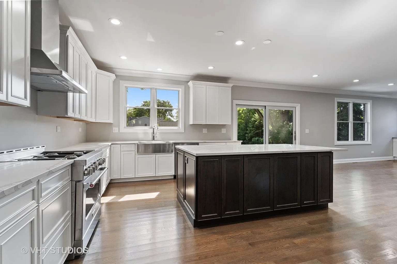 Open kitchen with white cabinets, dark island, and stainless steel range